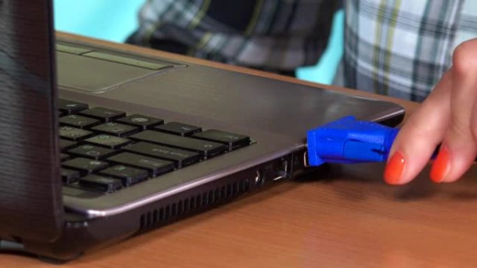 女性手动将vga显示电缆插入笔记本电脑。特写