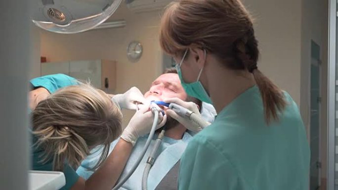 牙医钻了一颗年轻人的牙。助理帮忙。稳定。