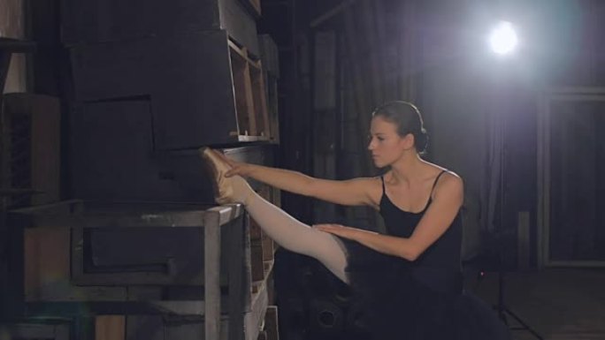 芭蕾舞女演员站在后台热身，然后上台表演舞台上的独奏节目。重复。芭蕾舞女演员在后台伸展