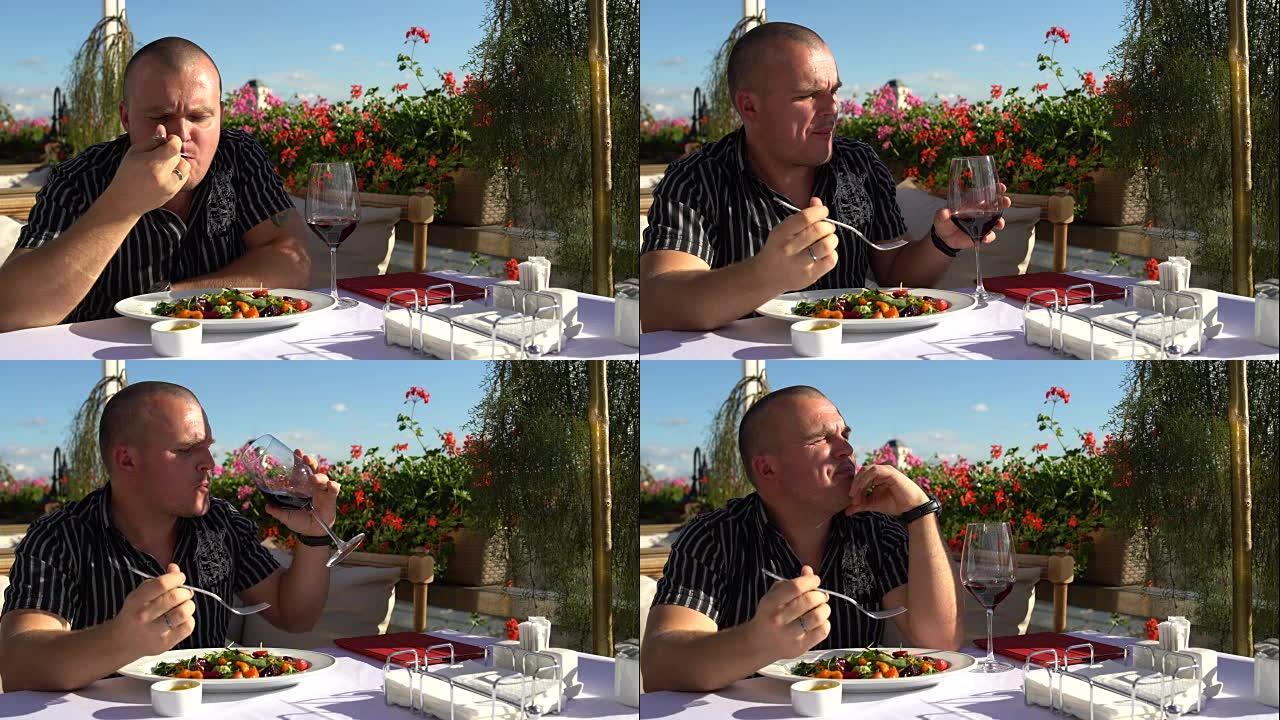 一名男子在餐馆吃沙拉和喝红酒