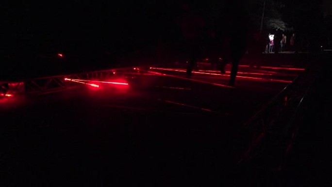 人们在公园夜灯秀中行走激光形成红线。全高清