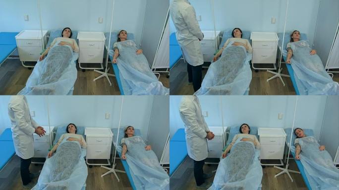 男医生检查两名女性病人躺在床上滴注