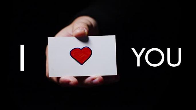 一只手展示了一张浪漫的卡片，上面写着 “我爱你”。概念: 爱，帮助他人，喜欢，激情，分享。