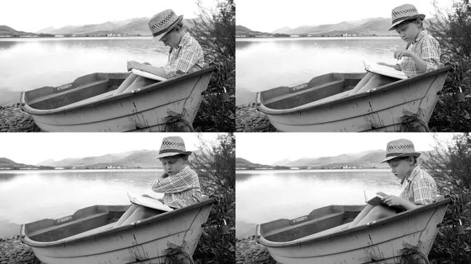 黑白画面:一个男孩坐在木船上看书