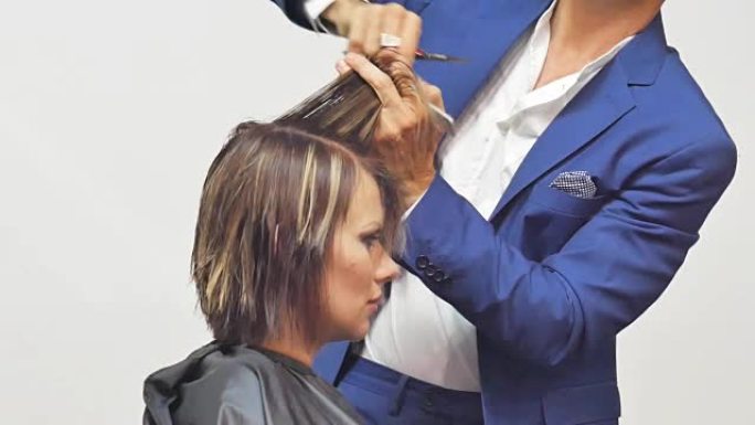 发型师用专业剪刀剪头发给年轻女孩