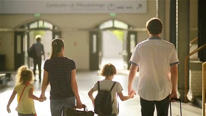 幸福的家庭，有小男孩和小男孩去火车站，母亲父亲和孩子们带着手提箱穿过机场