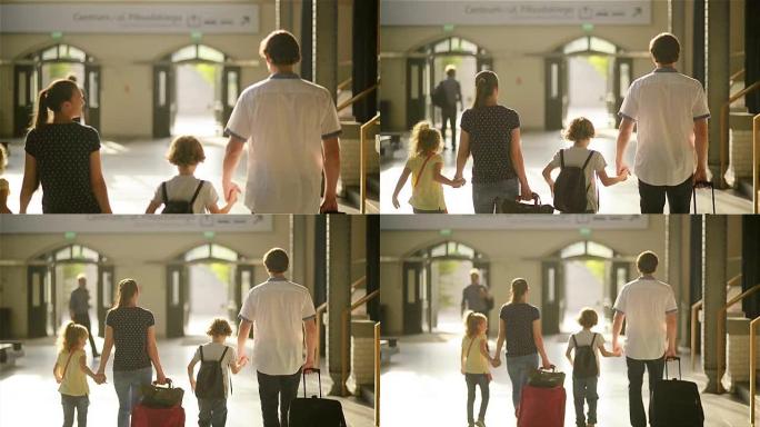 幸福的家庭，有小男孩和小男孩去火车站，母亲父亲和孩子们带着手提箱穿过机场