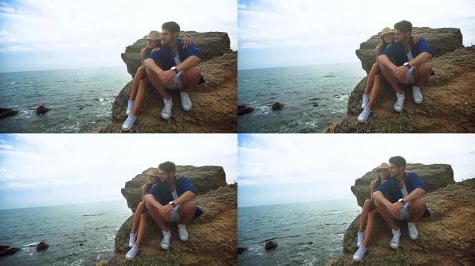 年轻的幸福夫妇穿着同样的白鞋坐在石头上，在沙滩上度过美好的一天