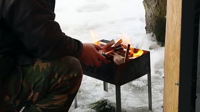 东欧: 生活方式。男子用煤气枪点燃烤架上的火木。