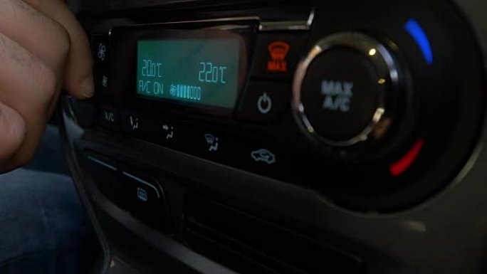 调节车内空调按钮的手特写。使用汽车空调系统的人