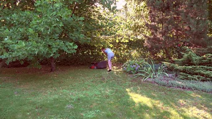 年轻女子在自己的绿色花园里和割草机一起工作。全高清