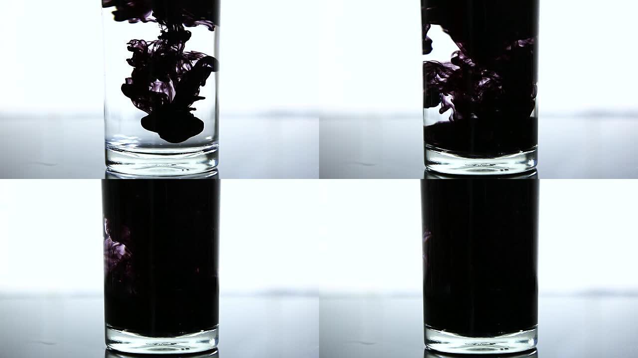 将黑色墨水倒入玻璃中的水中。慢动作