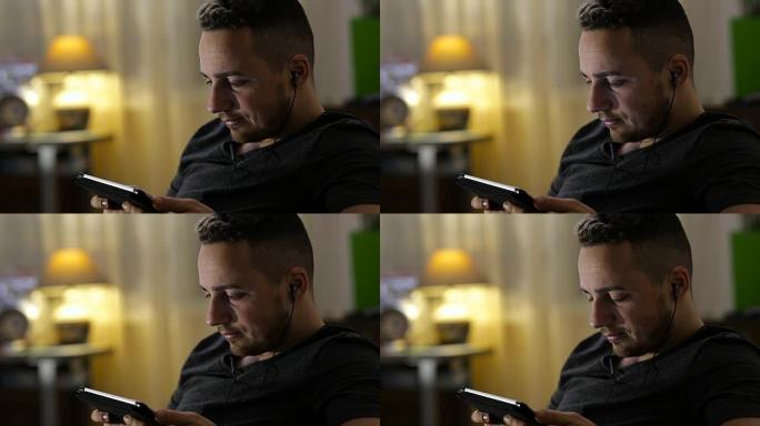 男人在家在平板电脑上观看视频或听音乐
