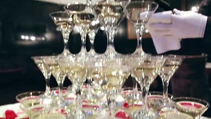 服务员在香槟鸡尾酒餐厅服务的玻璃塔里倒香槟