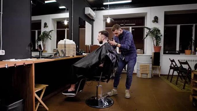 理发师将切割机应用于坐在理发店椅子上的客户