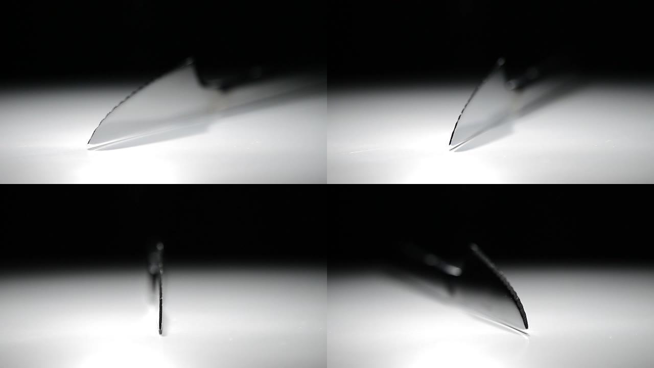 黑色背景的白色底座上旋转的金属刀