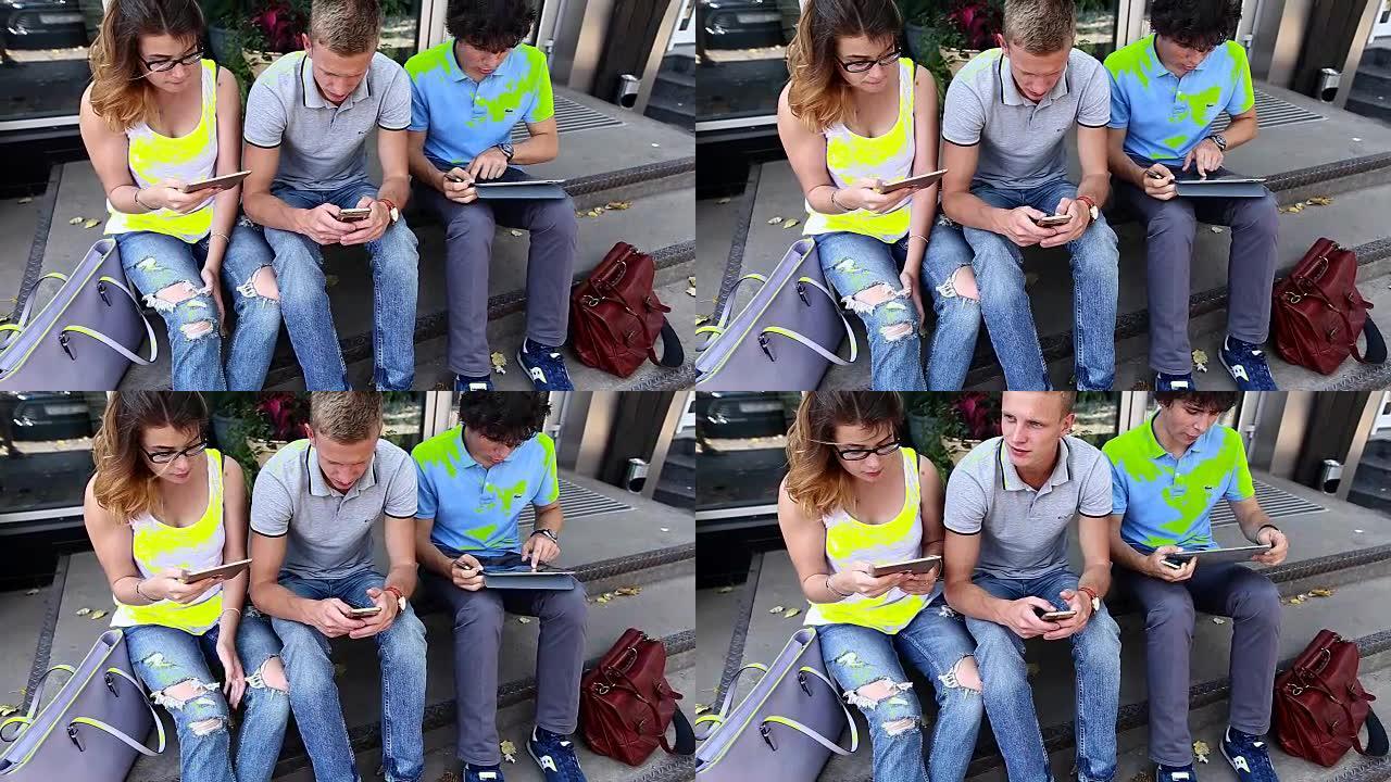 年轻的三个朋友坐在街上，聊天，使用