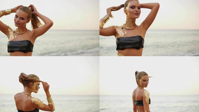 年轻迷人性感美丽的模特穿着泳衣在海滩上摆姿势。穿着黑色泳衣的女孩，皮肤金色，化妆专业，在海滩上在水边