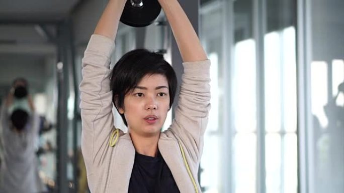 运动酷亚洲女子在健身房训练哑铃举重