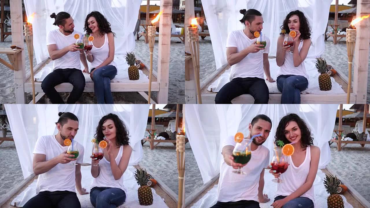 在海滩上休息，相爱的夫妇手里拿着鸡尾酒，男人和女人混合喝酒，朋友在热带地区喝鸡尾酒，年轻人喝酒
