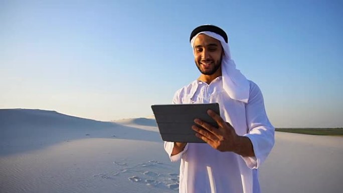 成功的阿拉伯商人手握平板，站在夏夜的大沙漠中