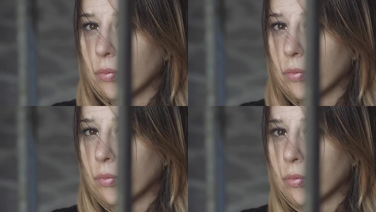 悲伤忧郁的女孩在监狱里，凝视着相机