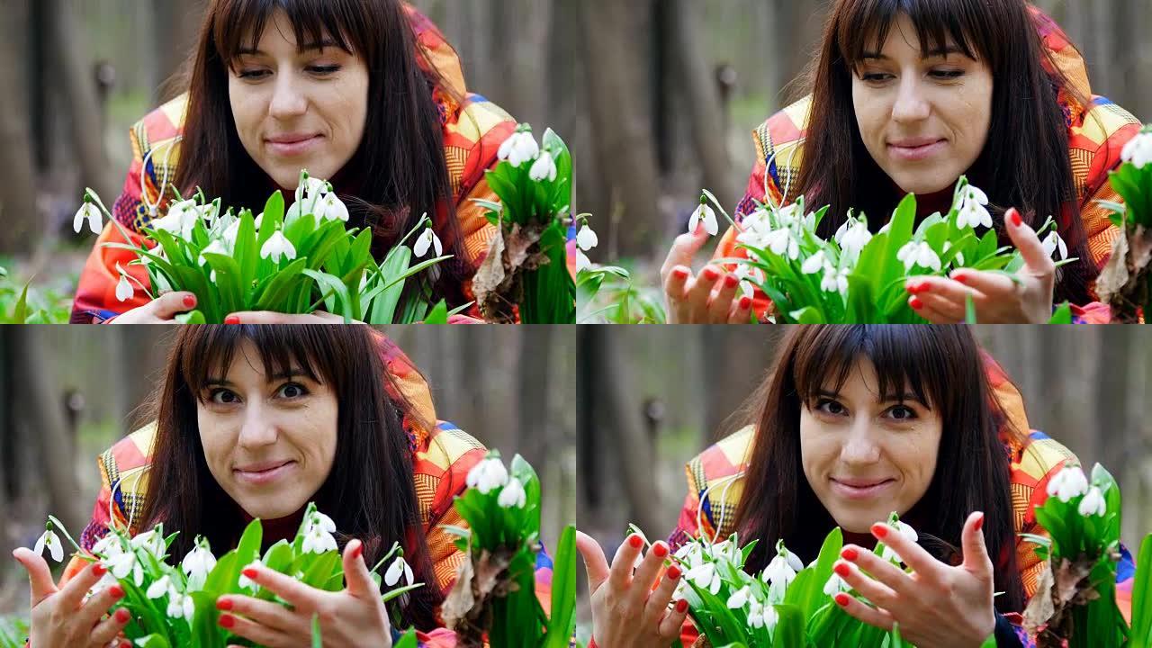 一个美丽的女人在春天的森林里享受着盛开的雪花莲