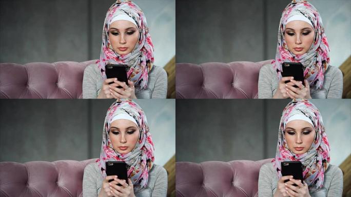 现代穆斯林妇女与智能手机。现代明亮多彩的头巾的概念