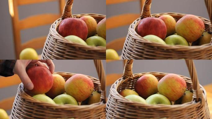 成熟的苹果躺在编织的檐口中。灰色背景。自然的阳光。摄像机从左到右移动。男性手进入画面，会选择最美丽的