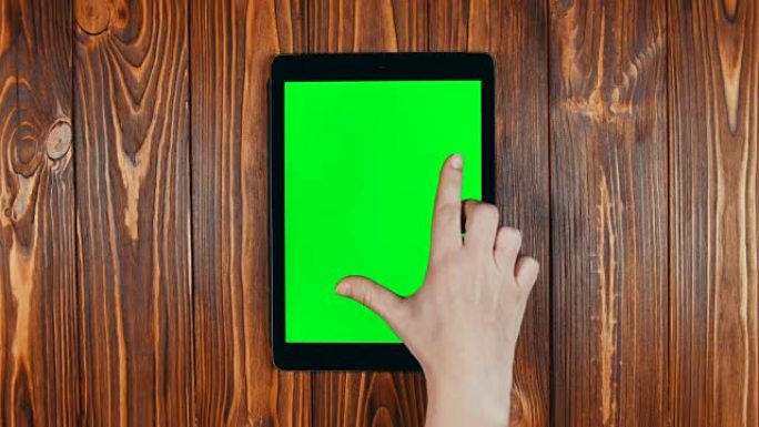 手指在平板电脑的绿色屏幕上滑动。缩小手势