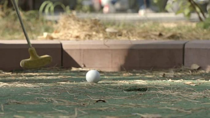 慢动作: 小球员将高尔夫球打向洞
