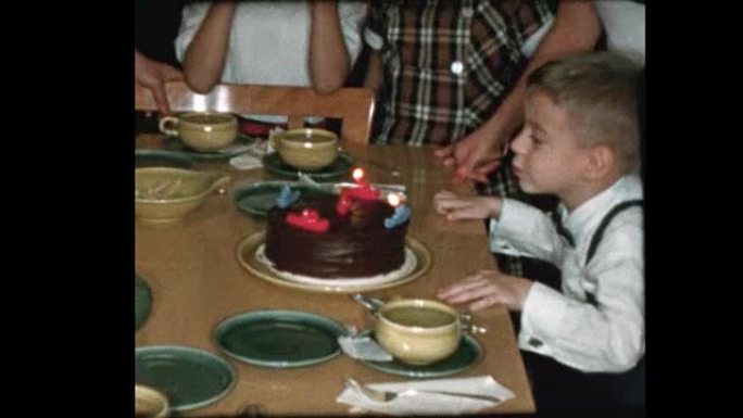 5岁的孩子吹灭生日蜡烛和家人唱歌