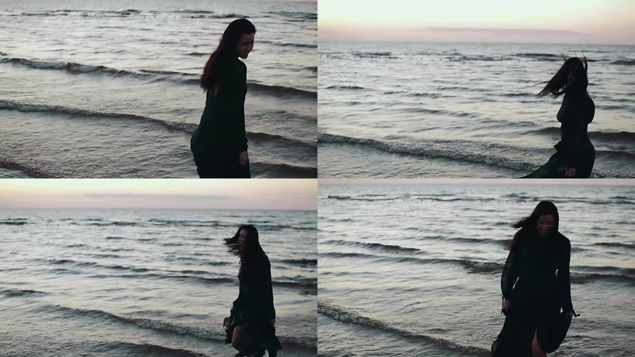 穿着深色连衣裙的女孩在海岸的水上摇头舞。拍照。模。海