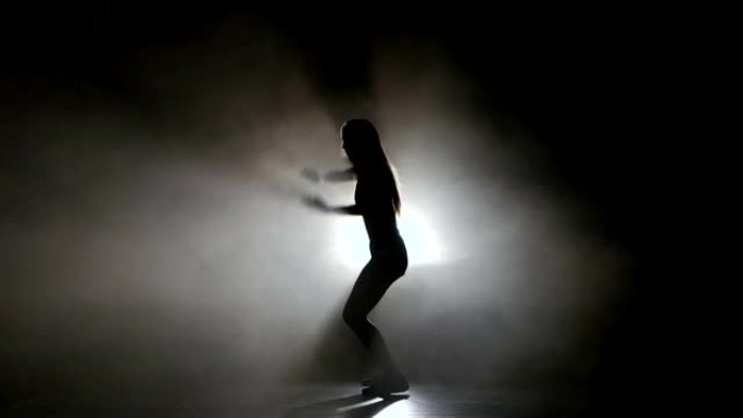 性感女孩在烟雾弥漫的工作室舞蹈中跳舞。剪影