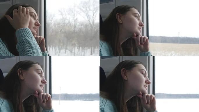 坐火车时看着窗户的年轻女子。冬天在铁路上旅行的迷人女孩的简介。特写