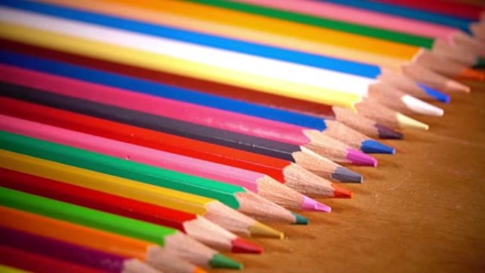 鲜艳的彩色铅笔在木制表面上排成一排