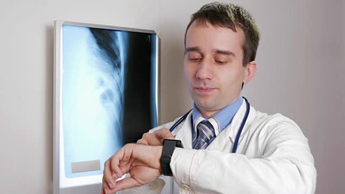 一位年轻的医生在诊所使用智能手表。男人口述病人的x光检查结果