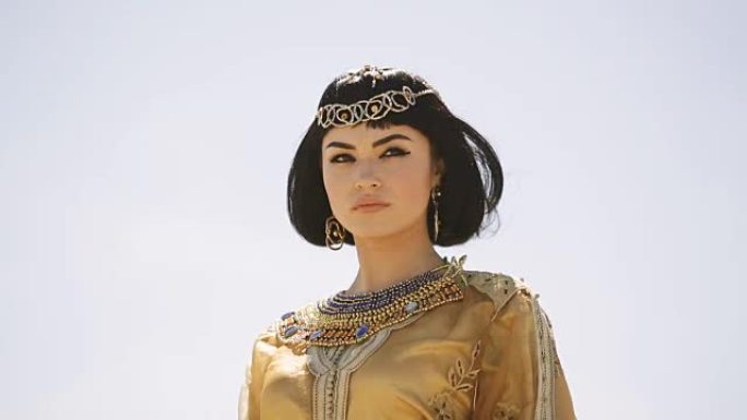 美丽的女人，穿着时尚的妆容和发型，像埃及女王埃及艳后，在户外抵御沙漠大风天气