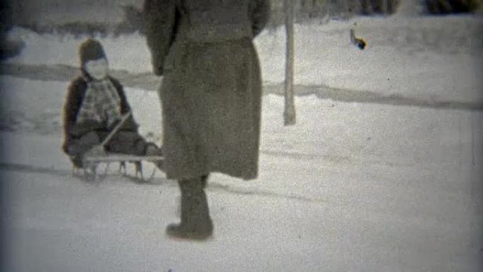 1938: 爸爸在院子里拉着女儿在冬天的雪橇上走来走去。