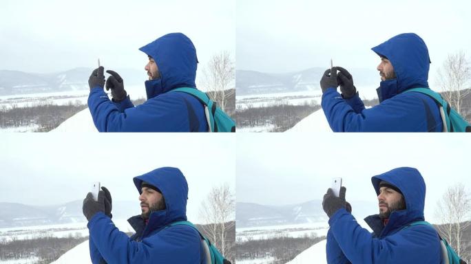在山上使用智能手机的胡须旅行者。穿着夹克的白人男子在寻找全球定位系统信号。登山者冬季移动通信。冒险探