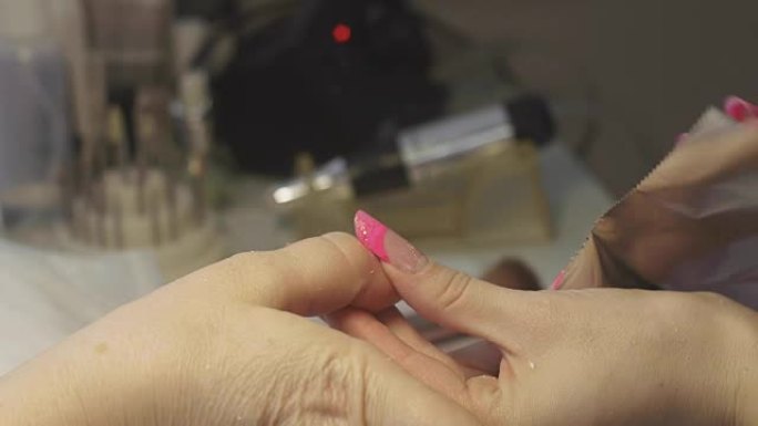 美甲师将特殊的溶剂涂在指甲上，以妇女在美容院包裹箔纸。虫胶盖的拆卸