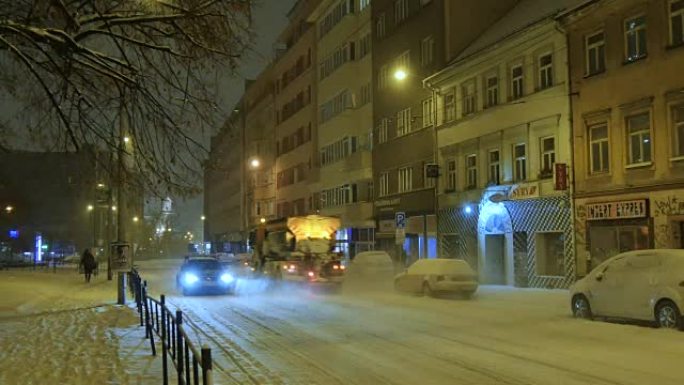 扫雪机骑在中欧白雪覆盖的街道上，晚上