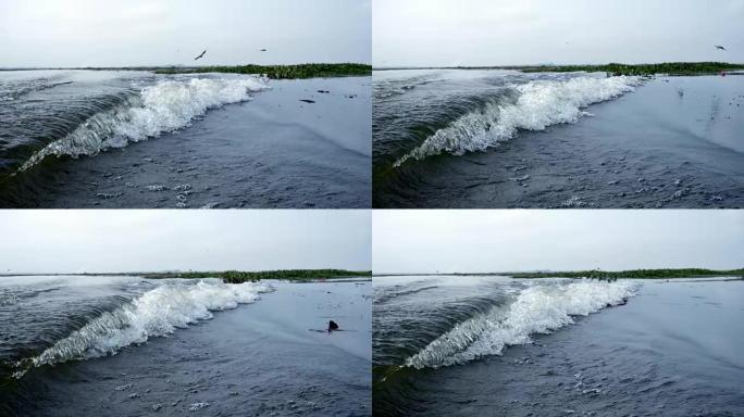 长尾船漂浮在湖上，在泰国乌隆他尼的浮云下，水面上有波浪