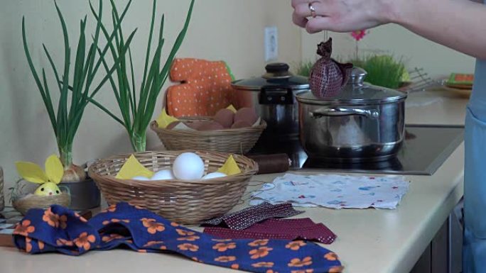 女性双手将白鸡蛋放入丝绸材料中。复活节彩蛋画。