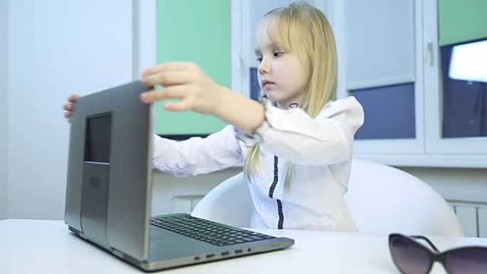 小女孩关上笔记本电脑，戴上眼镜。