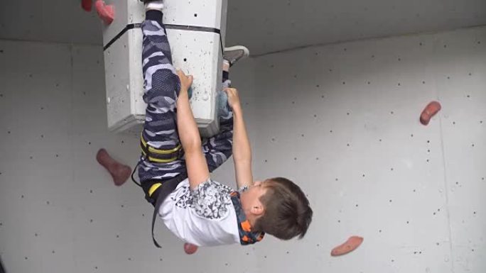 小家伙在运动健身房锻炼攀岩。在攀岩墙上训练登山者