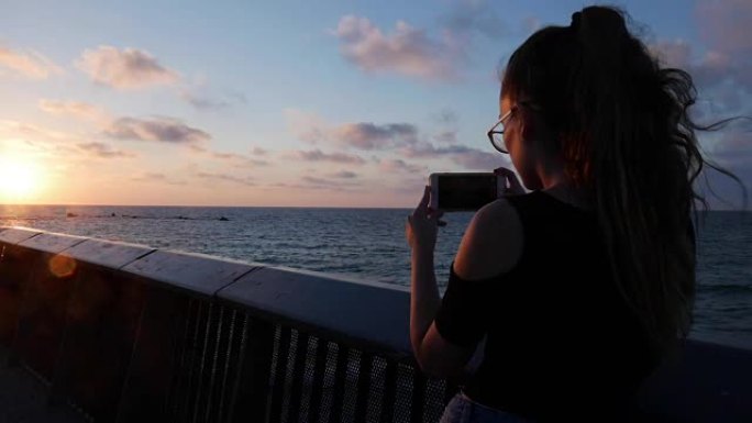 年轻女孩在特拉维夫的地中海贾法拍摄美丽的日落照片。