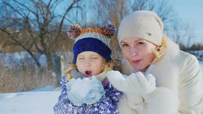 妈妈和女儿玩得开心5年了。祝冬天快乐，吹走手中的雪