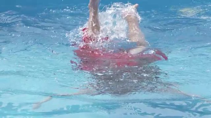 穿着红色长裙的女孩在水下游泳的游泳池水面