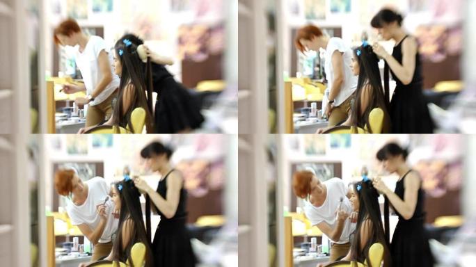 化妆师为迷人的女孩做漂亮的化妆，理发师做发型，广角